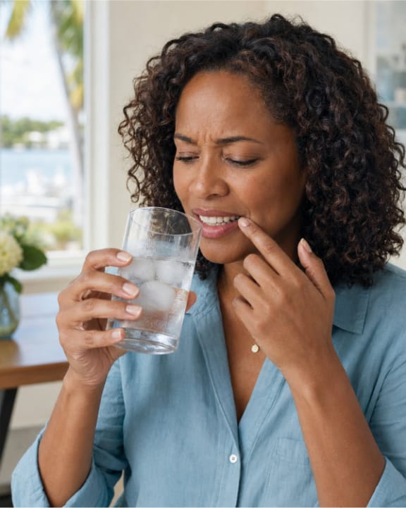 A person reacting to sensitivity while drinking a cold beverage
