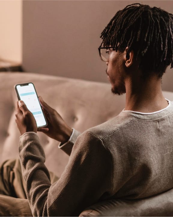 Man using a smartphone while seated on a sofa